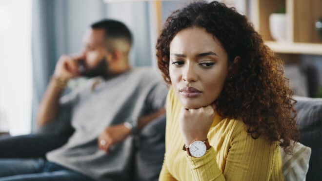 Black couple sitting apart on the couch - infertility