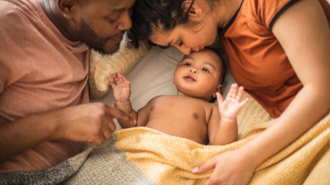Weekend's family life. African American parents with daughter on bed.