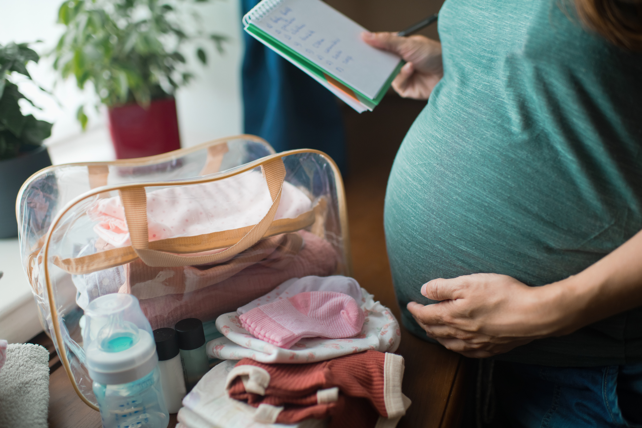 Pregnant woman at home preparing bag for newborn baby