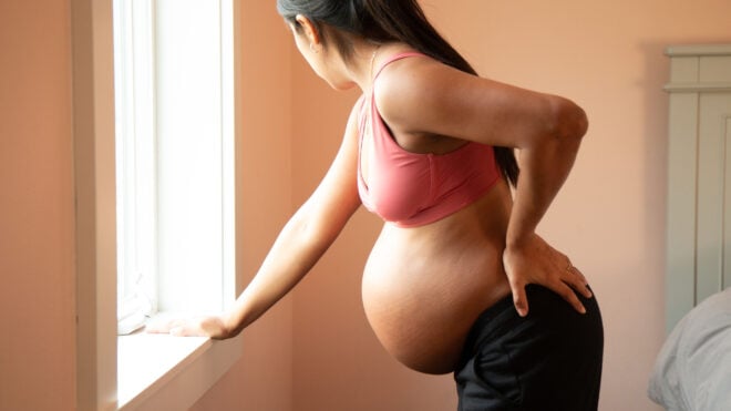 signs labor is close, Young pregnant hispanic woman coping with labor back pain.