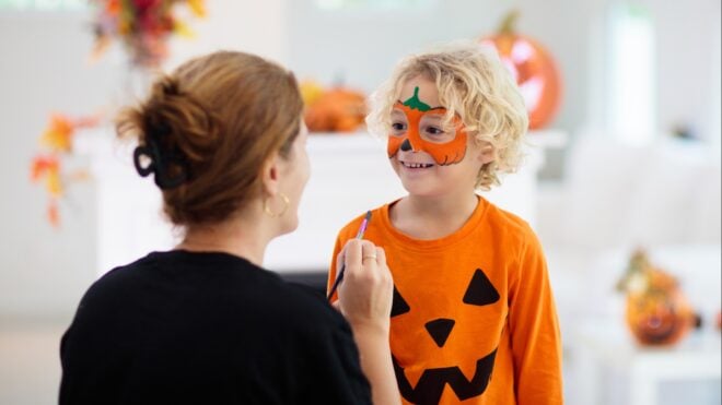 A mom getting her son ready for Halloween