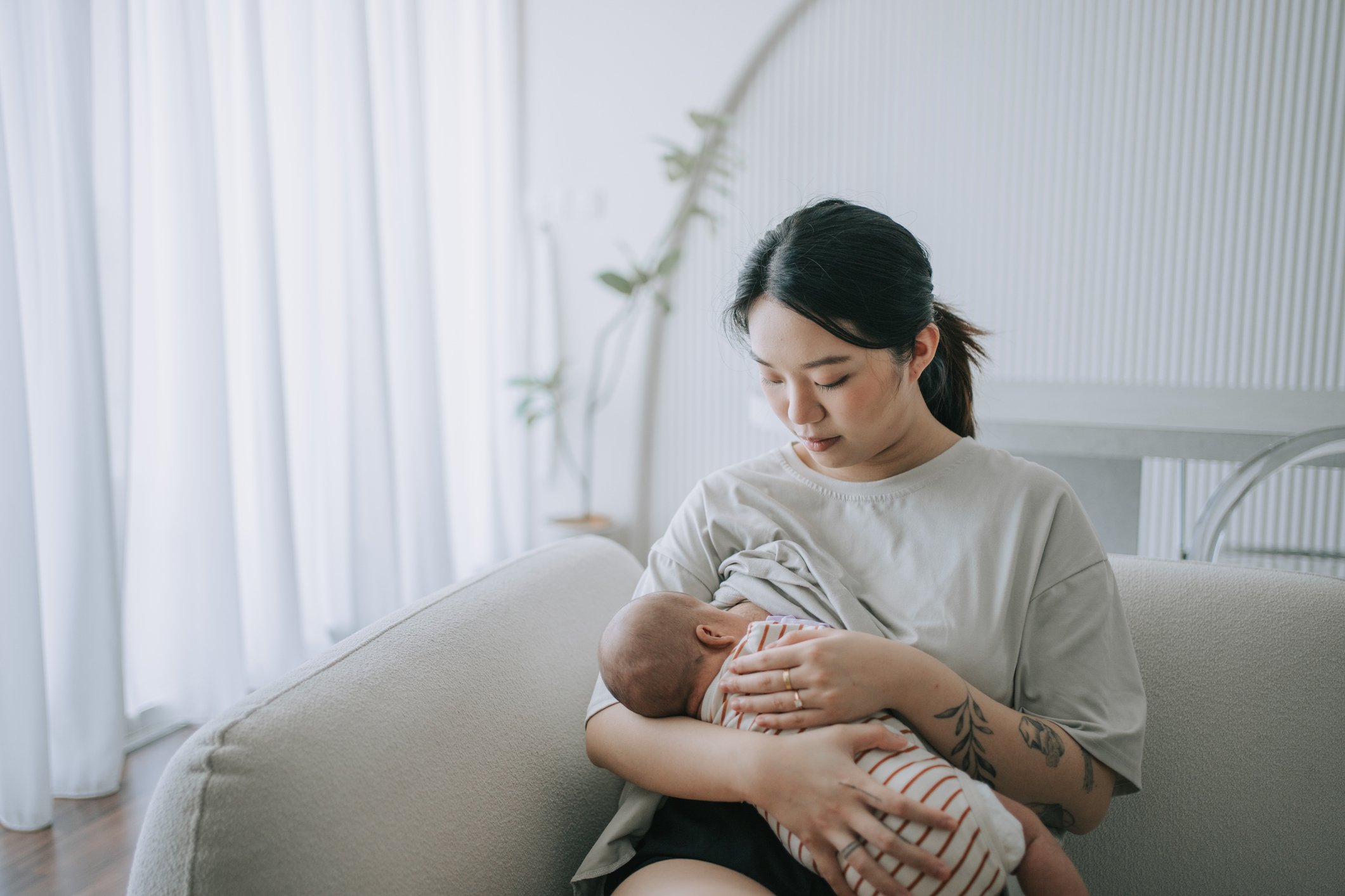 Asian Chinese young mother breastfeeding baby girl at home