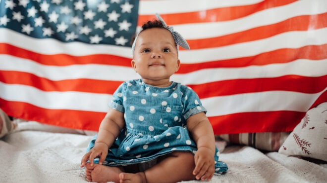 baby girl sitting in front of an American flag