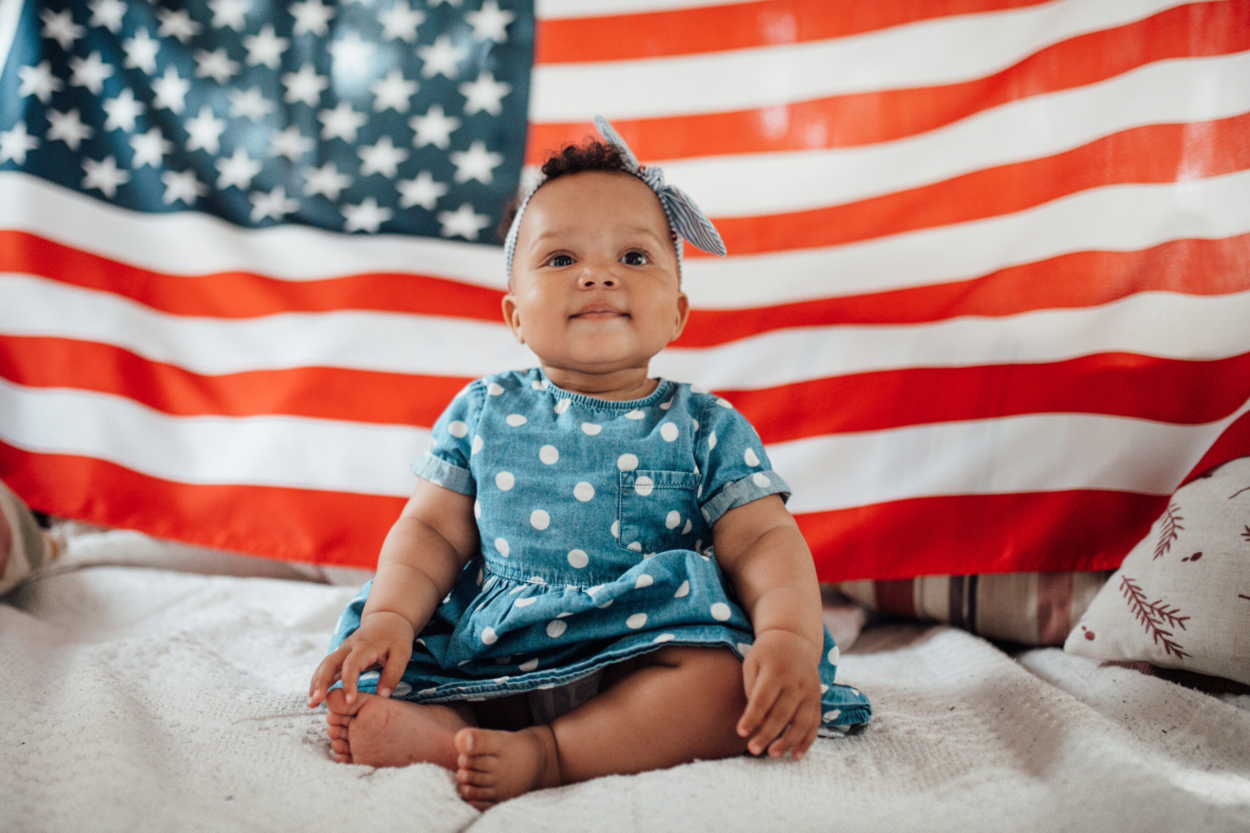 baby girl sitting in front of an American flag