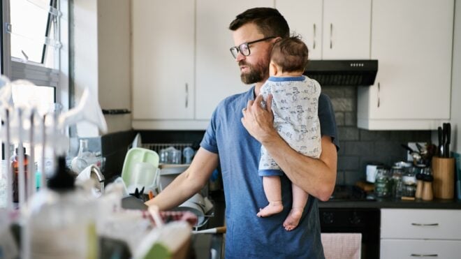 Dad busy at home with baby and chores.