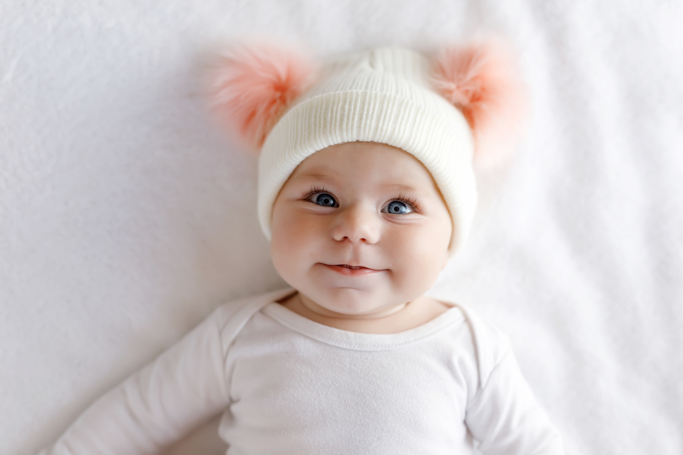 Cute adorable baby child with warm white and pink hat with cute bobbles