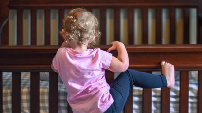 Toddler climbing on crib